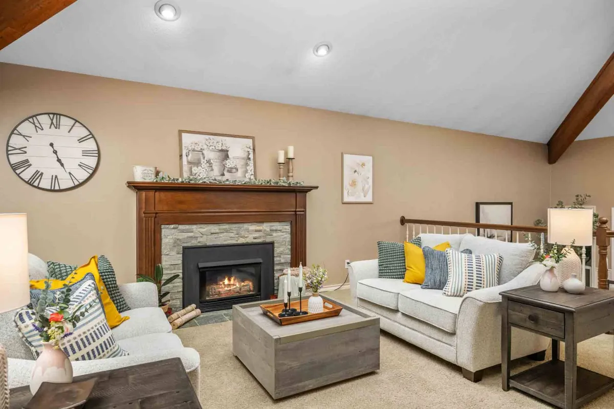 This image showcases the heart of the living area, featuring a welcoming fireplace, plush sofas, a coffee table, and tasteful wall art. The overall scene exudes comfort and warmth, with seating arranged for both relaxation and easy conversation.