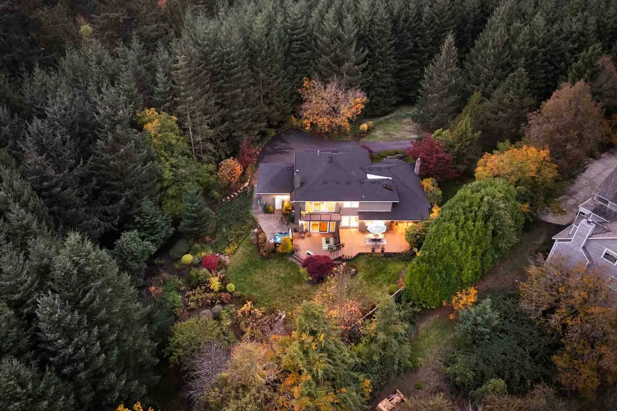 This exterior shot captures the house illuminated at dusk, with surrounding trees and a landscaped garden creating a tranquil, intimate atmosphere. The soft lighting and natural setting highlight the serene environment, perfect for romantic evenings or stargazing after a day of exploration.