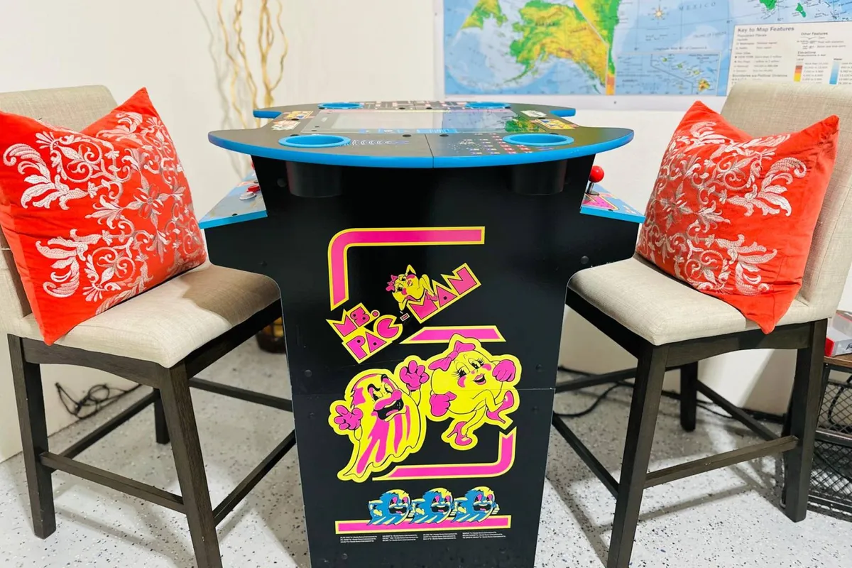 A cozy corner featuring a Ms. Pac-Man arcade machine paired with colorful cushions, inviting guests to indulge in nostalgic gaming sessions. The casual setup reinforces a sense of informal fun and friendly competition.