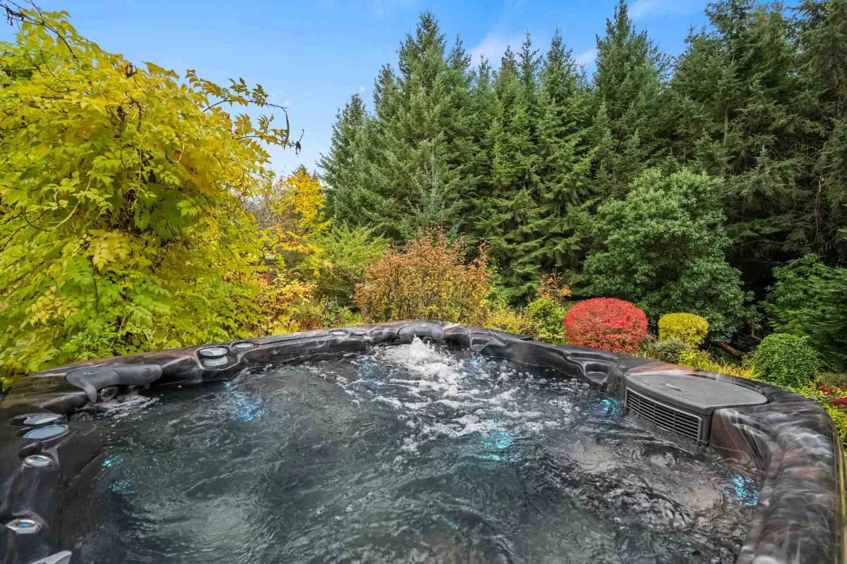 An inviting hot tub set among vibrant greenery and colorful foliage, surrounded by tranquil natural beauty. The hot tub area is private and peaceful, offering a perfect spot for stargazing or unwinding after a day outdoors.